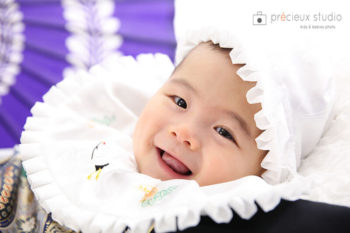 お宮参りの赤ちゃん記念写真 白いよだれかけと祝い着の赤ちゃん