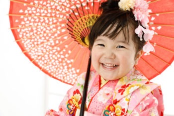 ピンクの着物に和傘で笑顔の七五三写真撮影