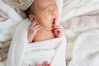 ニューボーンフォト撮影 王冠をかぶったおくるみのあくびしている赤ちゃん