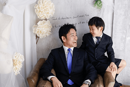 お父さんと目を合わせてほほ笑む新小学校一年生の男の子の入学記念写真