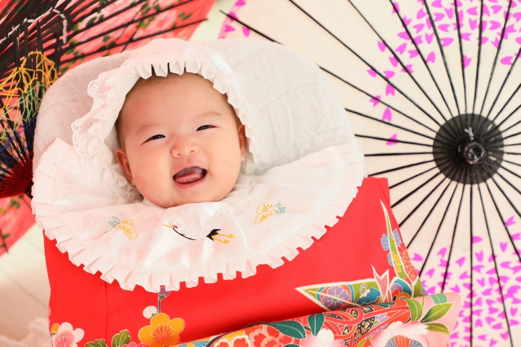 女の子のお宮参りの記念写真 赤い祝い着におめでたい鶴の刺繍のよだれかけ