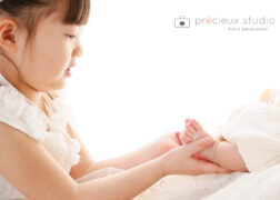 姉妹でお宮参り記念写真 赤ちゃんの小さな足とお姉ちゃんの手