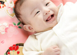 赤ちゃんのお宮参り記念写真撮影 ピンクの祝い着の上で笑顔の赤ちゃん