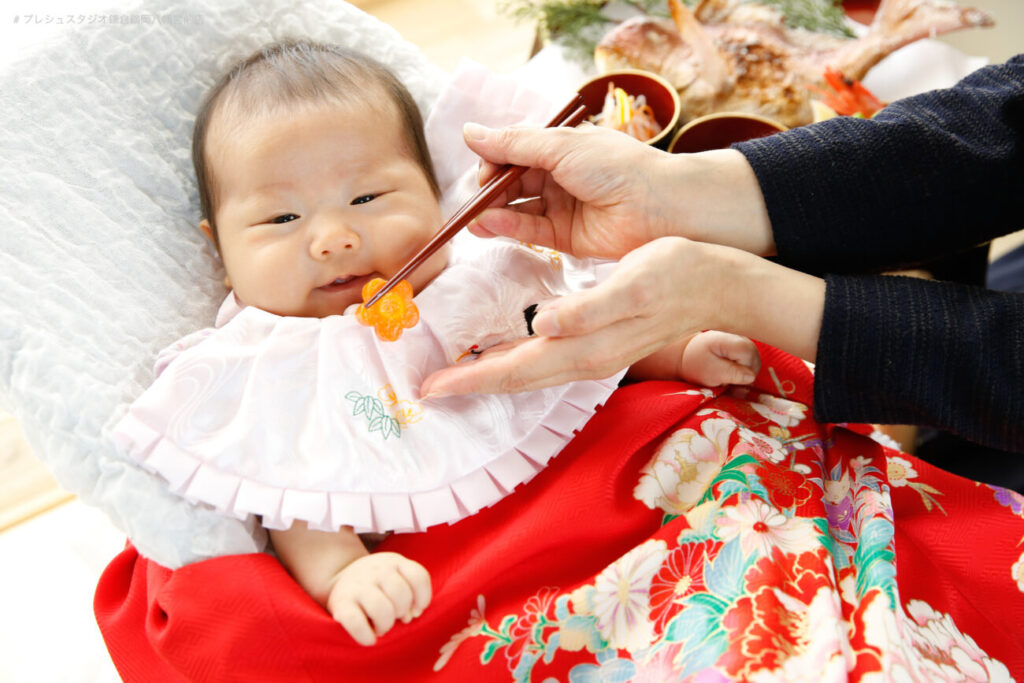 100日祝いのお食い初め記念写真撮影 赤い掛け着の女の子