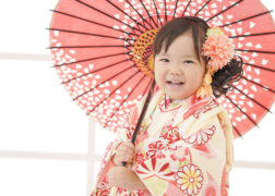 クリーム色の被布に赤い和傘で3歳の七五三写真撮影