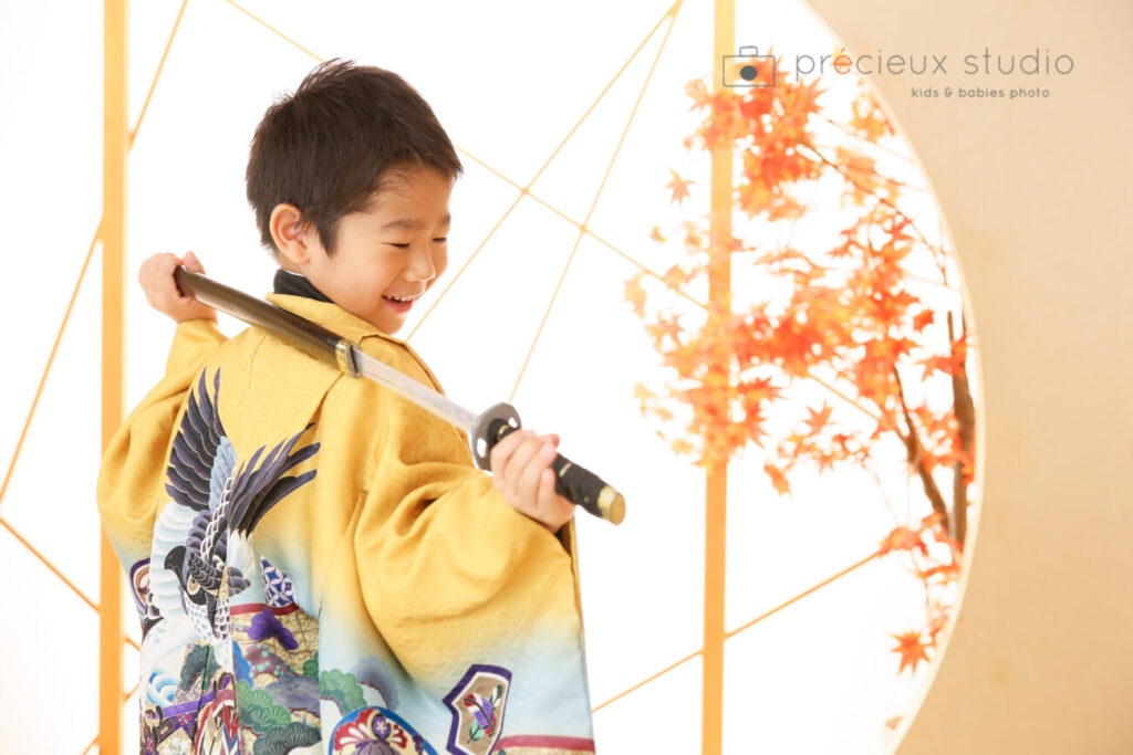 男の子の七五三写真撮影 黄色に鷹の羽織袴で日本刀を構えてポーズ