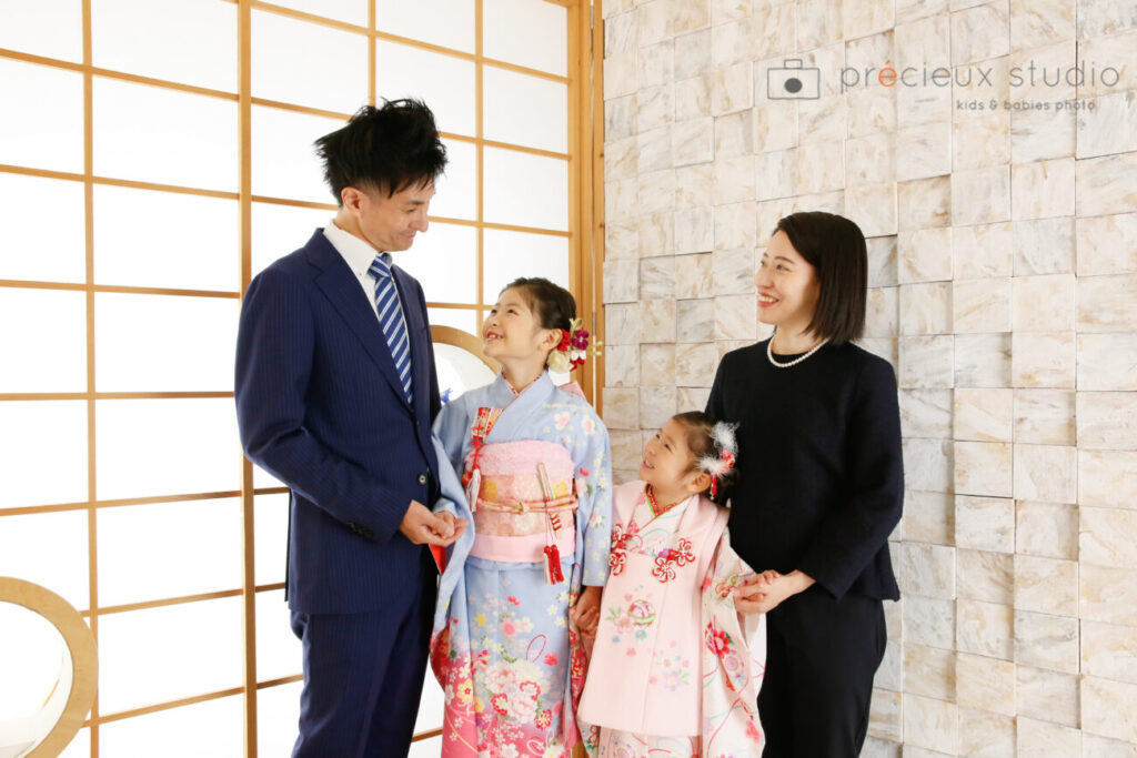 家族で七五三写真撮影 水色の着物のお姉ちゃんとピンクの被布の妹と両親
