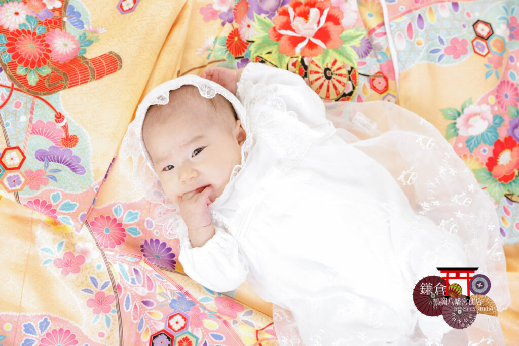 お宮参りの祝い着に寝転んでベビードレスで写真撮影の赤ちゃん