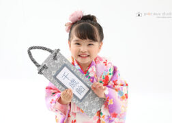 千歳飴を持って七五三記念写真撮影 ピンクの被布の3歳の女の子