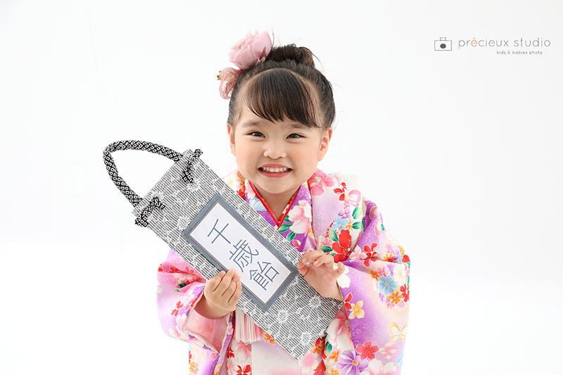 千歳飴を持って七五三記念写真撮影 ピンクの被布の3歳の女の子