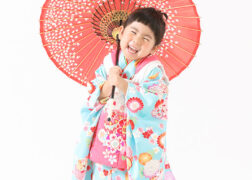 水色とピンクの被布を着た女の子 3歳の七五三記念写真撮影 和傘をさしてポーズ