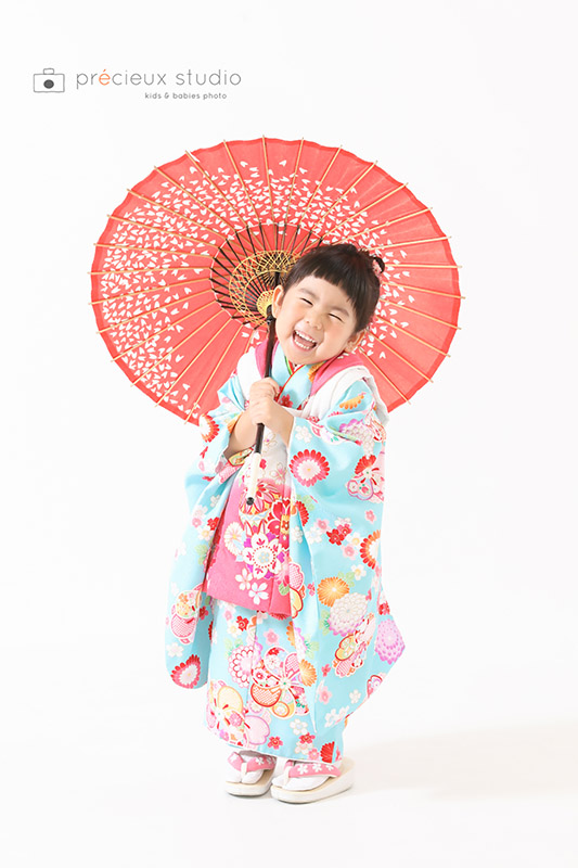水色とピンクの被布を着た女の子 3歳の七五三記念写真撮影 和傘をさしてポーズ