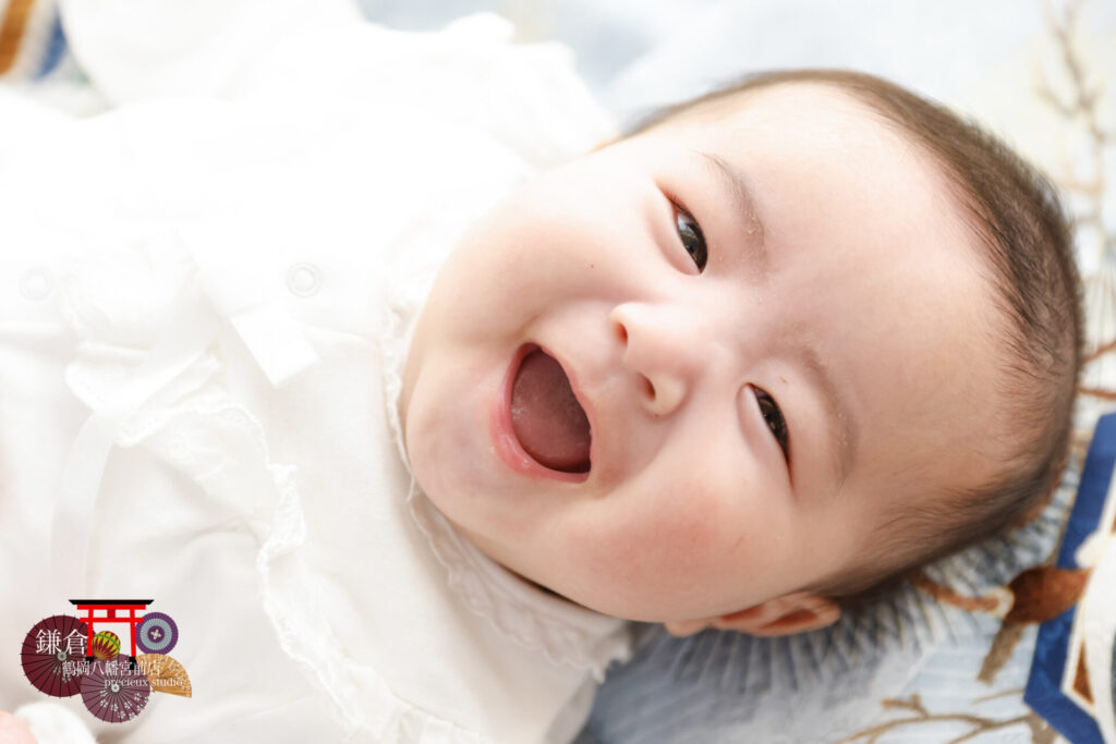 お宮参りの記念写真撮影 祝い着の上でにっこり笑顔の赤ちゃん