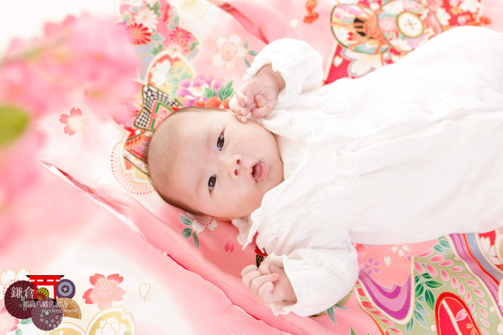 女の子のお宮参り記念写真撮影 ピンクの祝い着に寝転ぶベビードレスの赤ちゃん