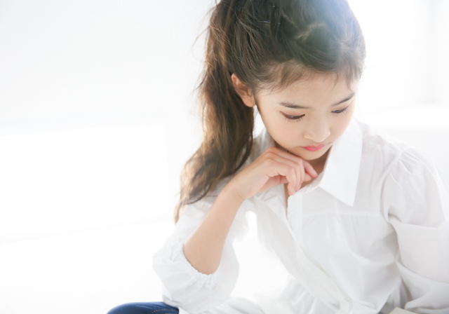 肘をついてうつむくお姉さん風ポーズでハーフ成人式の記念写真撮影 垢抜けた白シャツにデニム