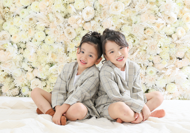 双子リンクコーデで記念写真撮影 おしゃれなセットアップとお花がいっぱいの背景