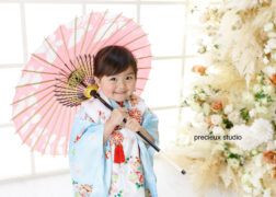 水色の着物で七五三写真撮影の女の子 ピンクの和傘を持ったポーズ