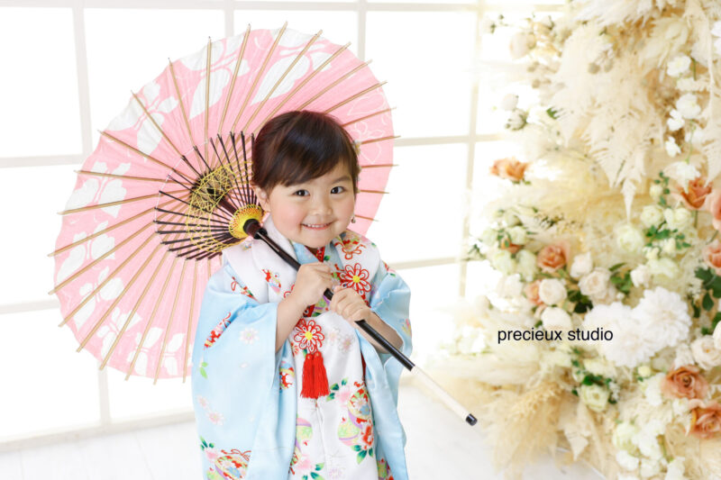 水色の着物で七五三写真撮影の女の子 ピンクの和傘を持ったポーズ