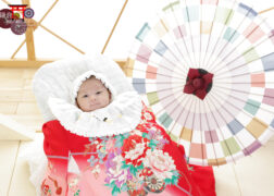 和室で赤ちゃんのお宮参り記念写真撮影 赤い掛け着・カラフルな和傘と一緒にスタジオ撮影の赤ちゃん