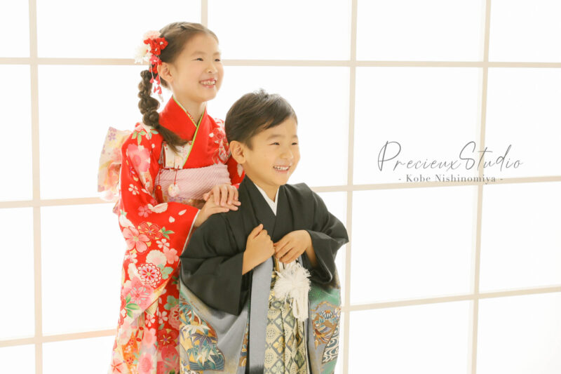 姉弟で七五三の記念写真撮影 赤い着物のお姉ちゃんと黒い羽織袴の弟