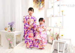 姉妹で七五三記念写真撮影 ピンクと紫の着物でお花に囲まれてポーズ