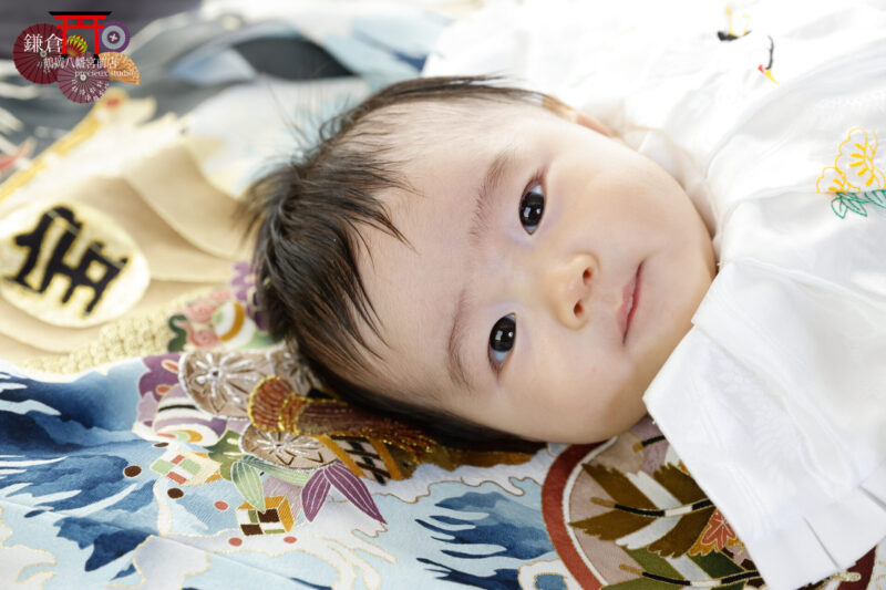 男の子のお宮参り記念写真撮影 掛け着に寝転んでカメラ目線の赤ちゃん