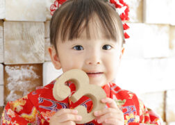 3のオブジェを持って3歳の七五三記念写真撮影 赤い着物の女の子