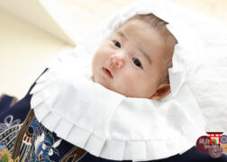 お宮参りの記念写真 掛け着・大黒帽子によだれかけで正装の男の子