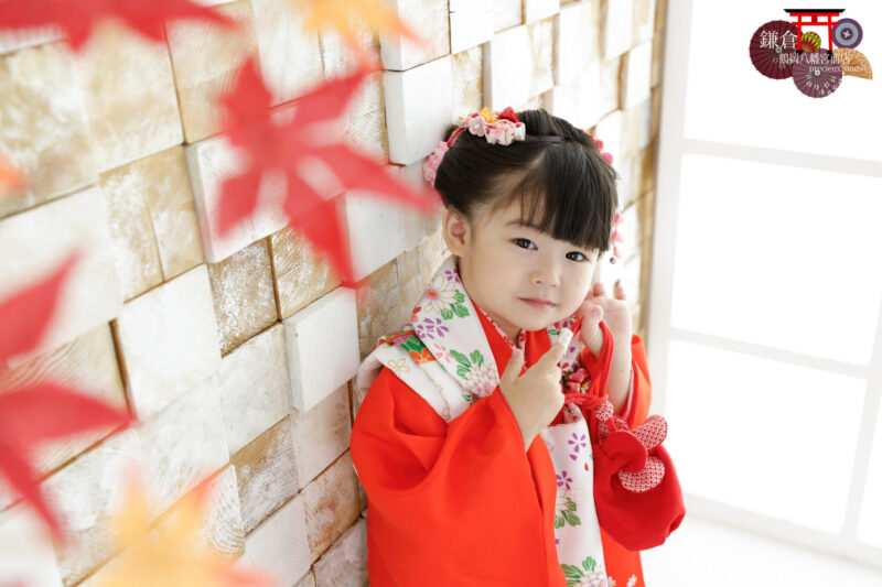 朱色の着物にピンクの被布で3歳の七五三記念写真撮影