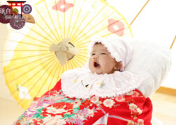 赤い掛け着を羽織って赤ちゃんのお宮参りの記念写真撮影
