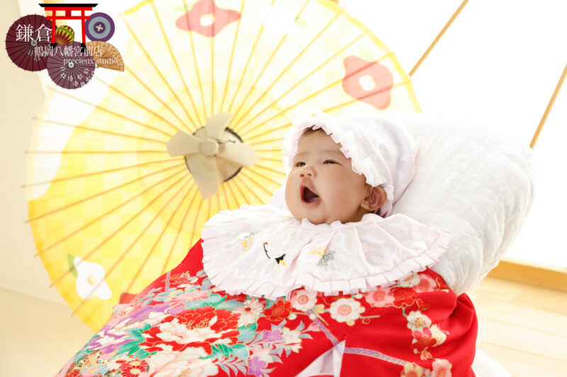 赤い掛け着を羽織って赤ちゃんのお宮参りの記念写真撮影