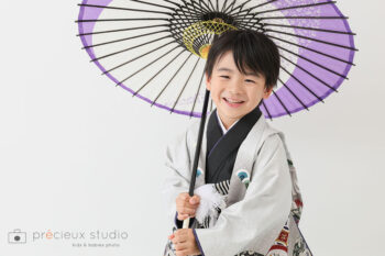 5歳の七五三記念写真撮影 グレーの羽織袴に和傘をさして笑顔の男の子