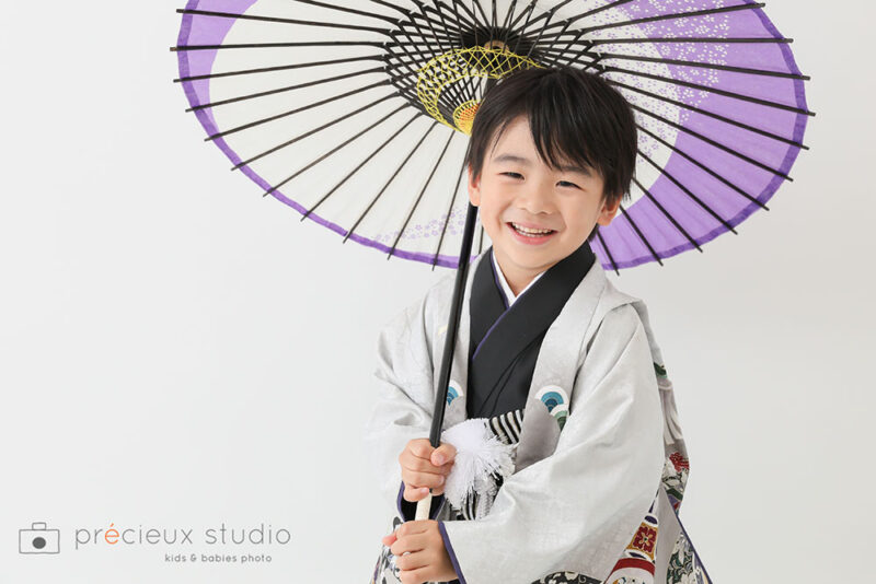 5歳の七五三記念写真撮影 グレーの羽織袴に和傘をさして笑顔の男の子