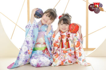 姉妹で七五三記念写真撮影 ピンクと水色の着物姿で手鞠を持ってポーズ