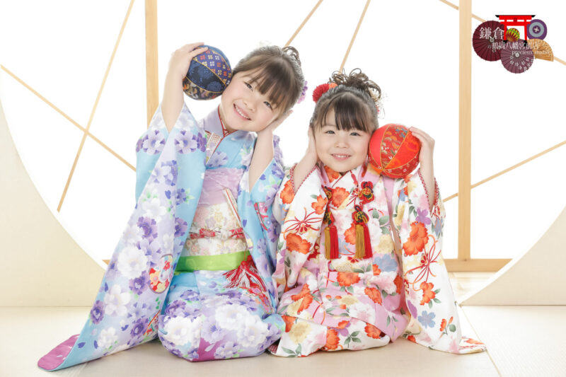 姉妹で七五三記念写真撮影 ピンクと水色の着物姿で手鞠を持ってポーズ