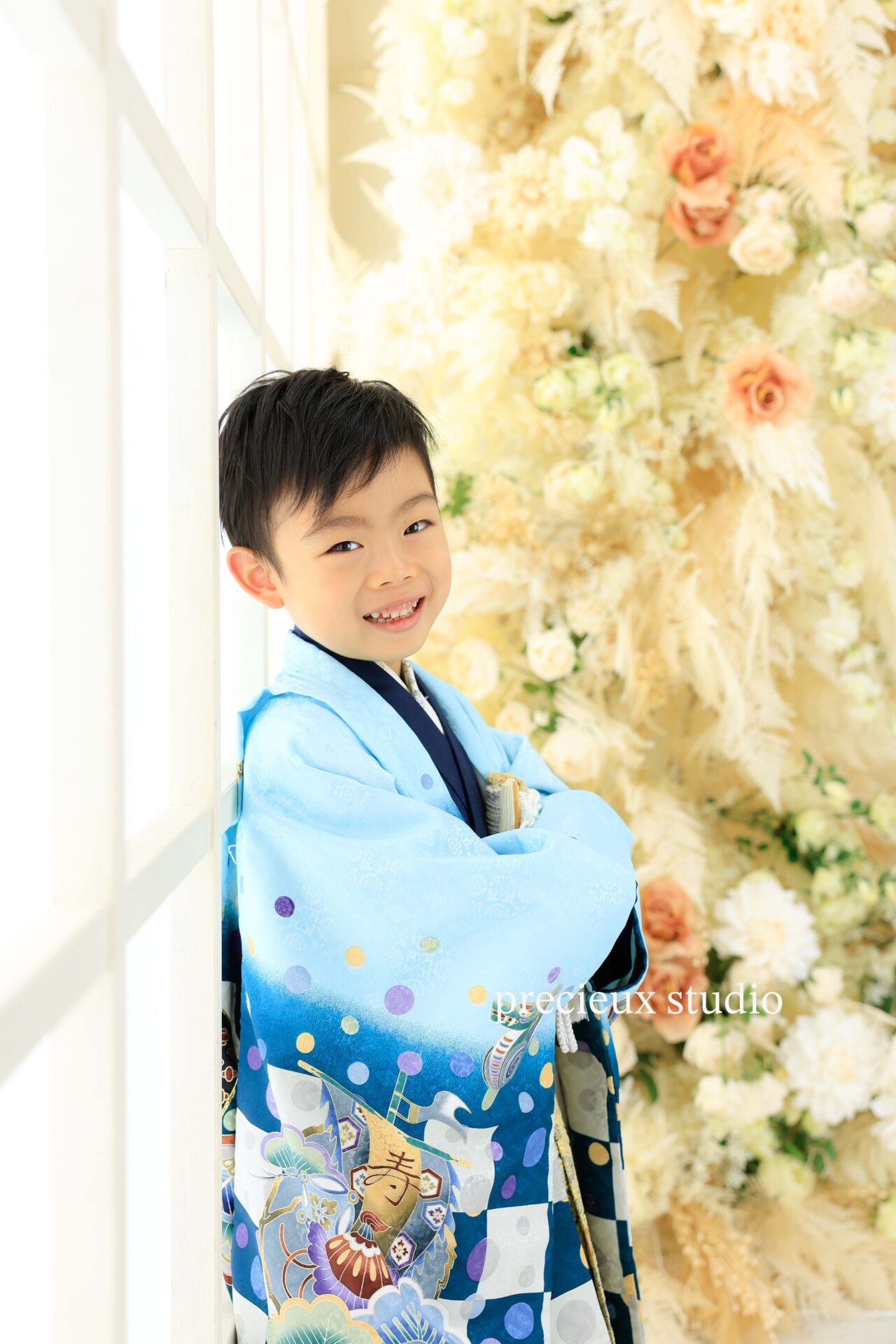 お花のセットを背景に水色の羽織袴で七五三写真撮影の男の子