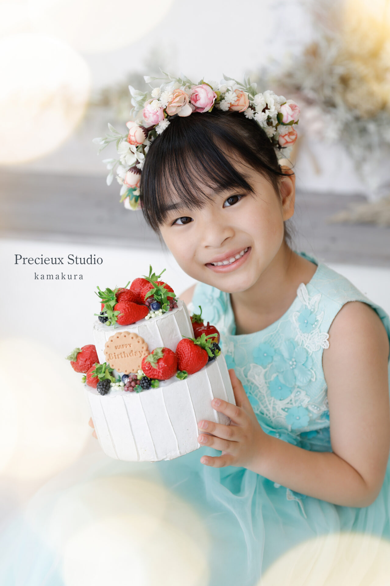 お誕生日の記念写真撮影 ケーキの飾りを持った花冠の女の子