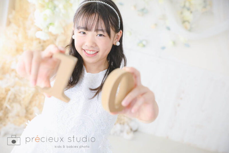 ハーフ成人式の記念撮影 白いワンピース姿の10歳の女の子